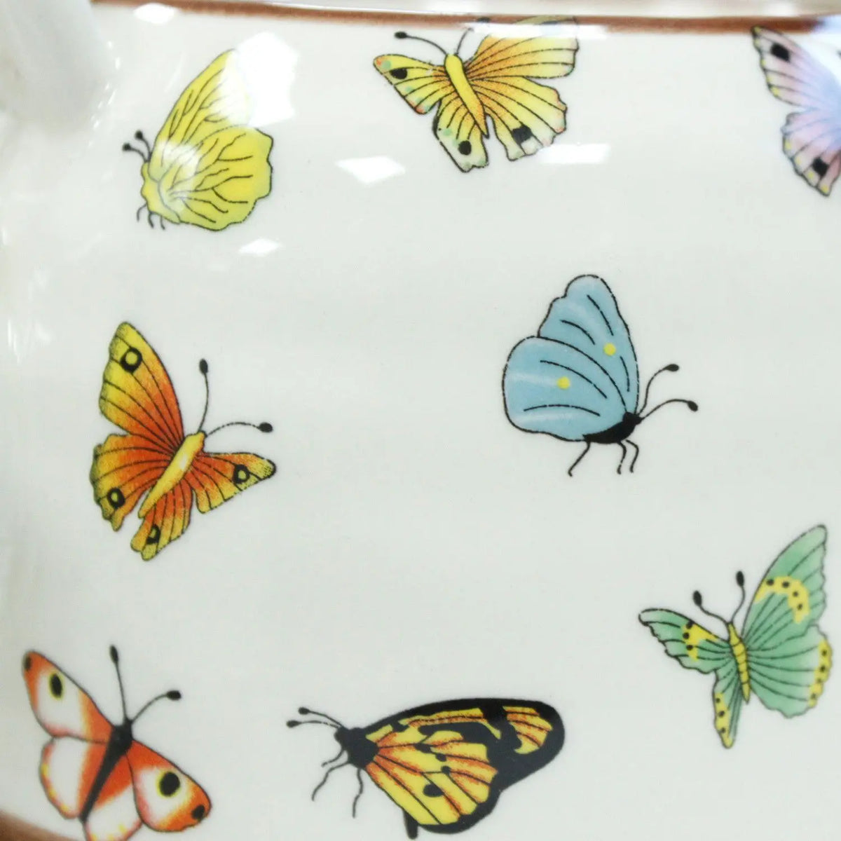 Taza de cerámica blanca con mariposas de colores brillantes: amarillas, naranjas, azules y verdes.