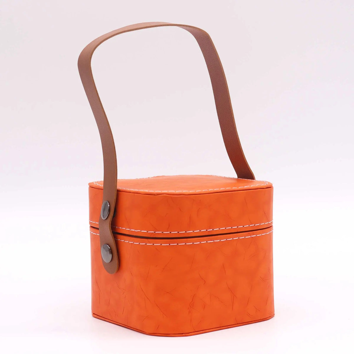 Estuche de viaje naranja de cuero sintético con costuras blancas, forma cuadrada y asa superior marrón con botones.