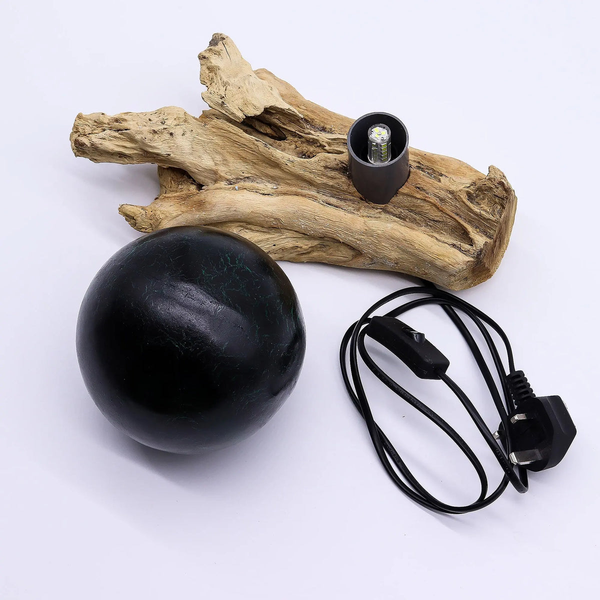 Lámpara de mesa con esfera verde esmeralda craquelada sobre base de madera natural y cable de alimentación negro.