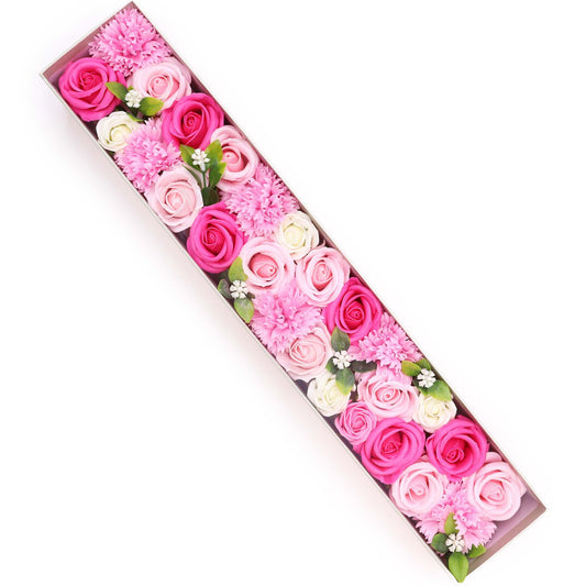 Caja alargada con flores de jabón en tonos rosa, blanco y fucsia, decorada con hojas y flores pequeñas. Fondo blanco.