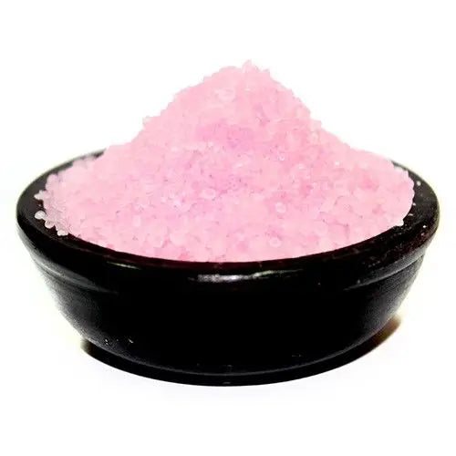 Pequeños gránulos aromáticos de color rosa en un cuenco redondo de color negro, sobre fondo blanco.