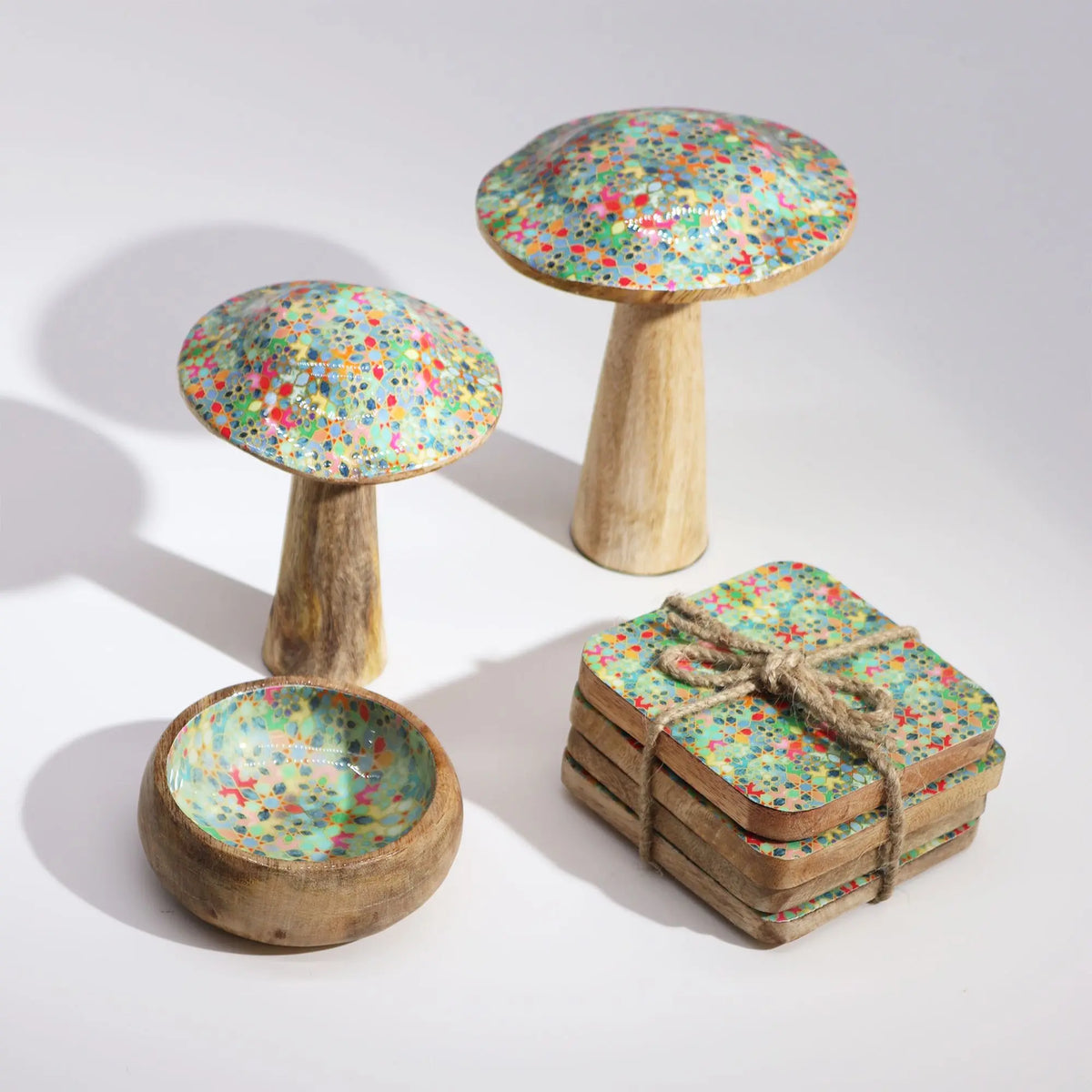 Set de decoración de madera con bases en forma de hongo y posavasos de color verde y flores multicolores.