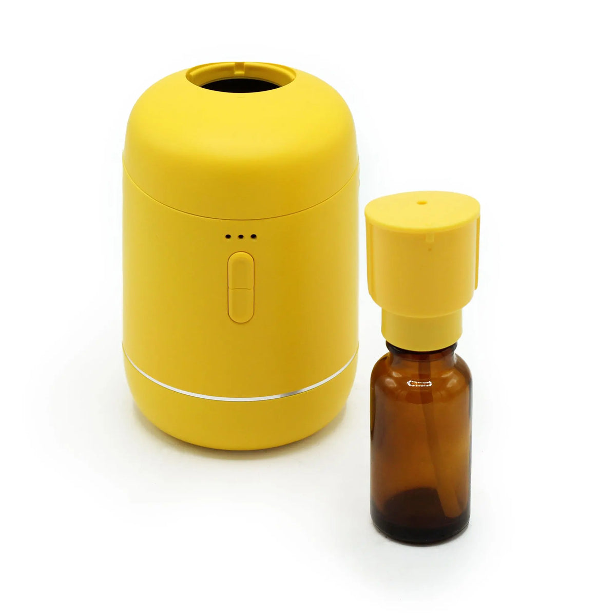 Difusor de aromas amarillo, cilíndrico y compacto, junto a un frasco de vidrio ámbar para aceites esenciales.