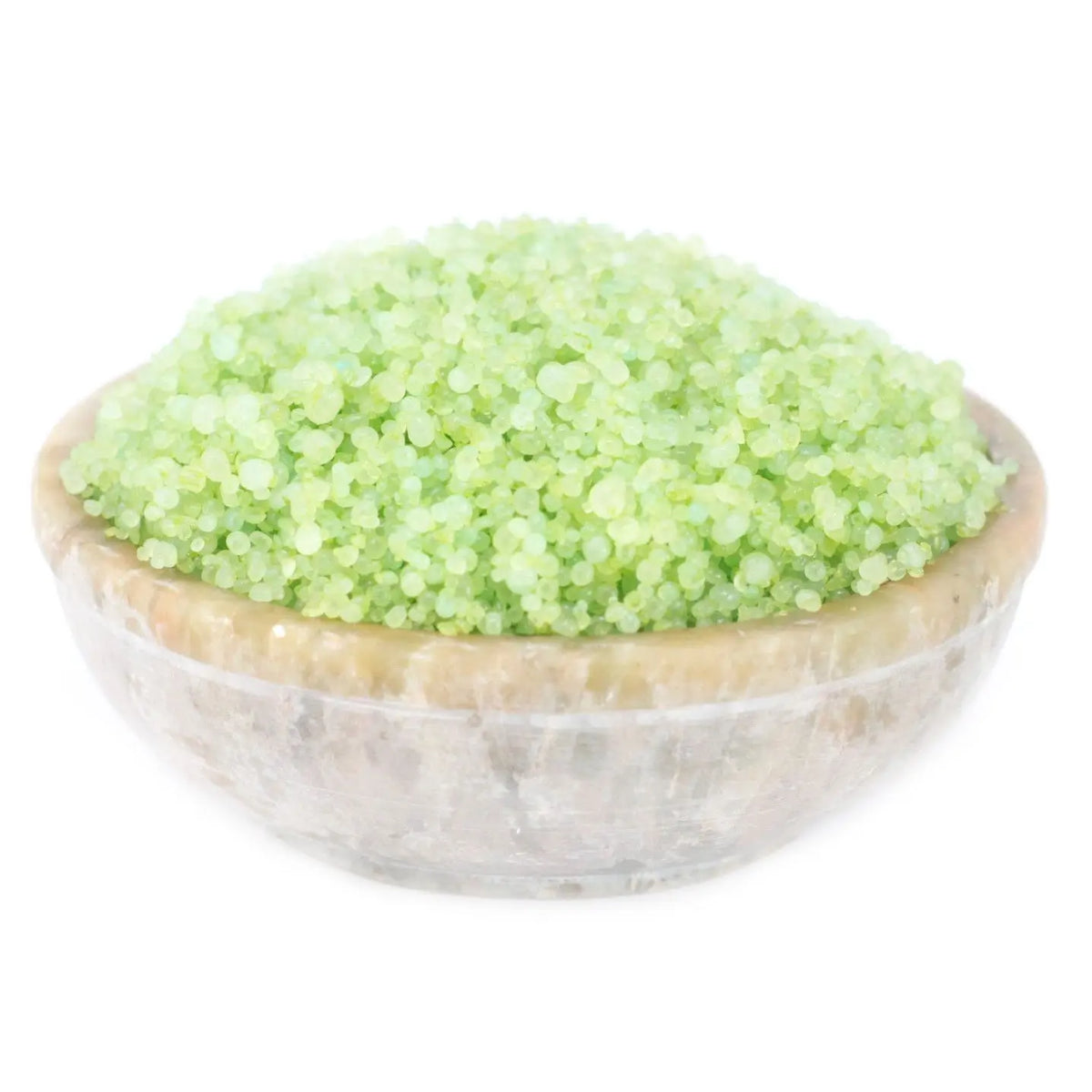 Cuenco de piedra natural conteniendo gránulos aromáticos pequeños de color verde lima, sobre fondo blanco.