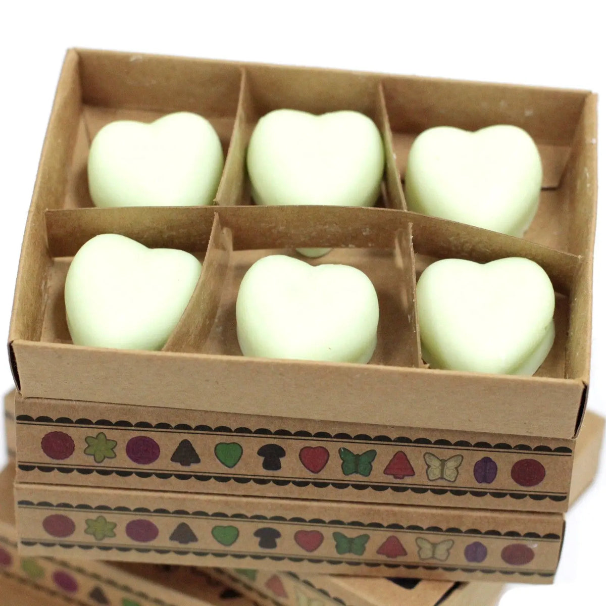Seis ceras de soja en forma de corazón, color verde claro, en una caja de cartón decorada con figuras geométricas.