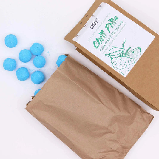 Mini bombas de baño efervescentes azules saliendo de una bolsa de papel kraft con etiqueta de lavanda y bergamota.