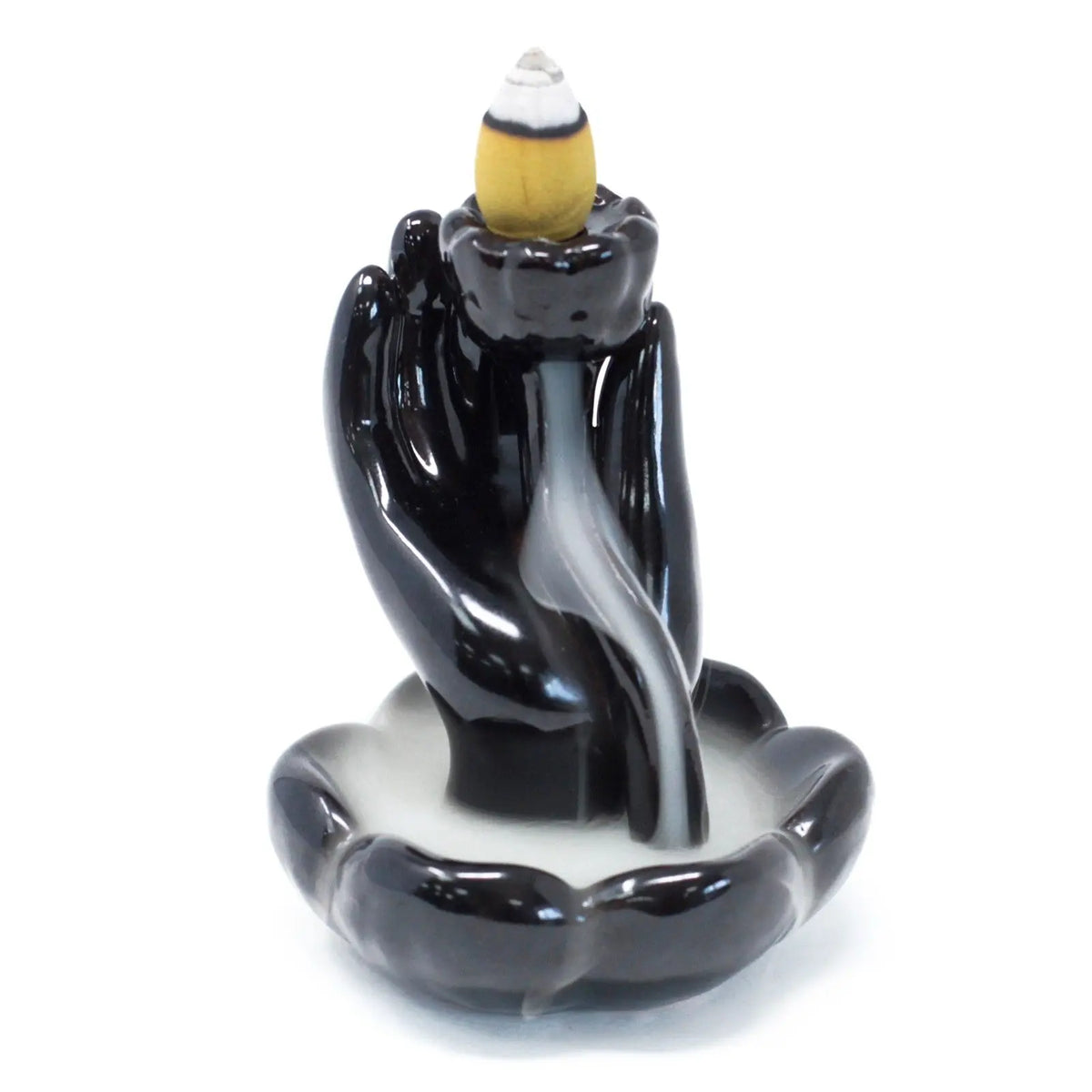 Quemador de incienso de cerámica negra con forma de mano sosteniendo una flor de loto y humo de flujo inverso.