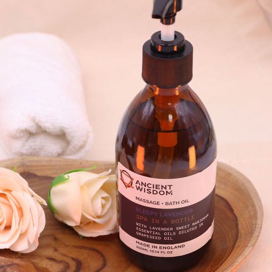 Botella de aceite de lavanda en envase ámbar con dosificador, sobre bandeja de madera junto a rosas y una toalla blanca.
