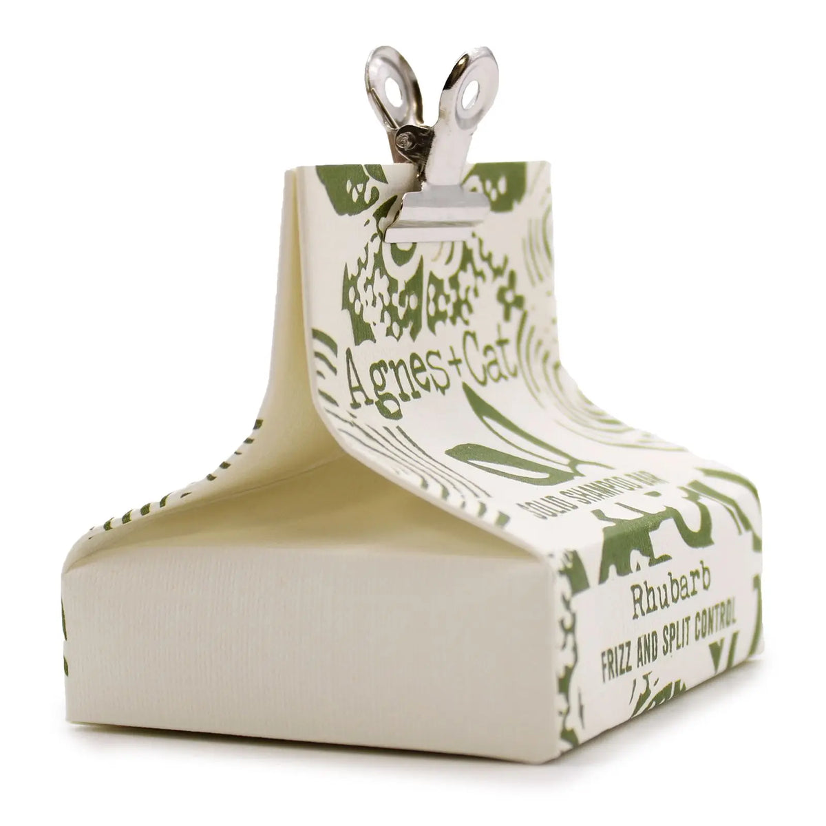 Champú sólido de ruibarbo Agnes + Cat en paquete de papel blanco con diseño verde y pinza metálica superior.