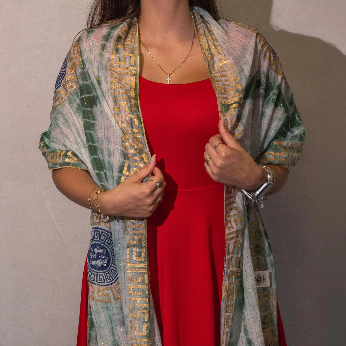 Chal verde y dorado con estampado griego, ideal para complementar vestido rojo. Perfecto para ocasiones elegantes.