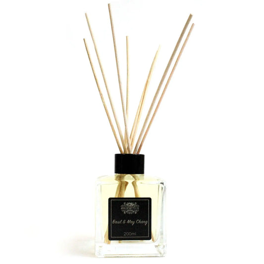 Difusor de varillas con frasco de cristal cuadrado, aceite esencial de albahaca y maychang y tapón negro sobre fondo blanco