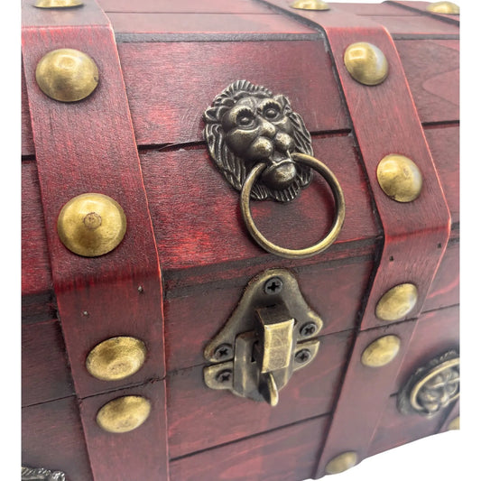 Cofre vintage de madera rojiza con herrajes dorados, detalle de cabeza de león y cierre metálico. Estilo colonial.