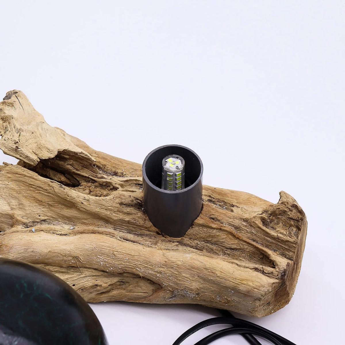 Lámpara de mesa con base de madera natural y soporte cilíndrico metálico que sostiene una bombilla LED expuesta.