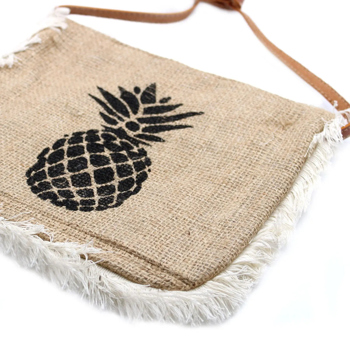 Bolso de yute color beige con estampado de piña negra, bordes deshilachados y correa fina, estilo tropical.