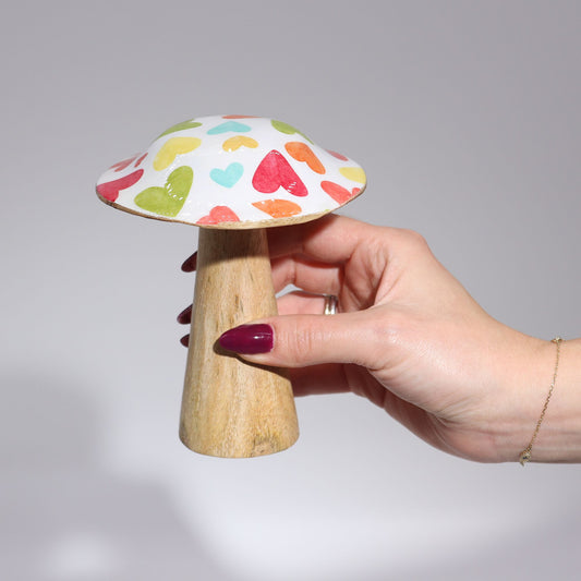 Seta decorativa de madera esmaltada con diseño de corazones en tonos pastel sostenida por una mano femenina