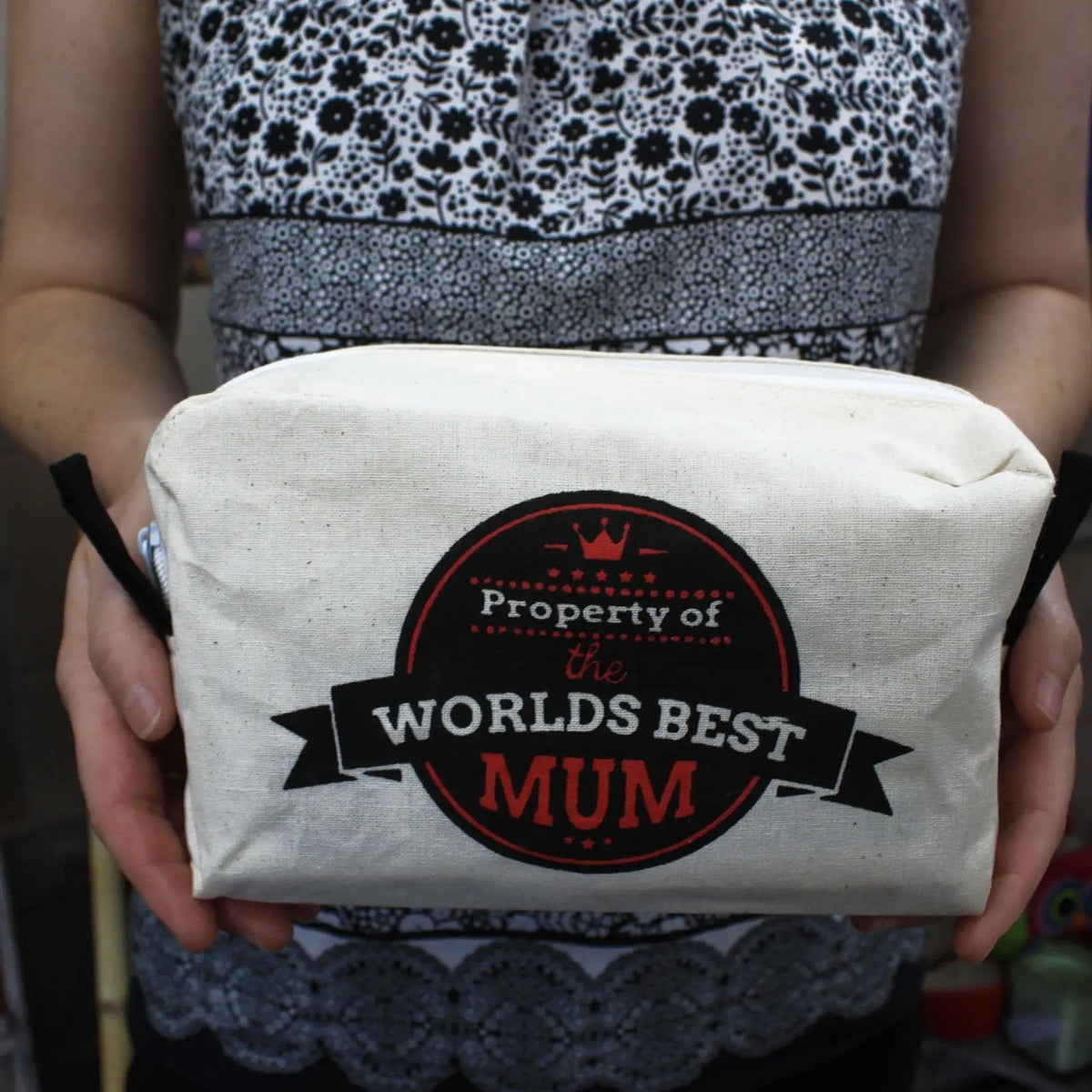 Neceser de algodón natural beige con mensaje "Property of the world's best mum" en un círculo rojo y negro.