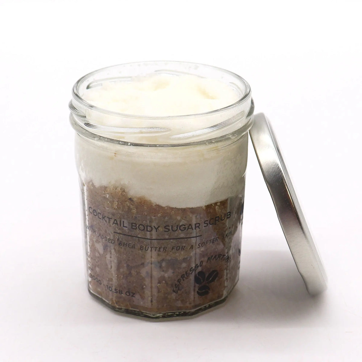 Exfoliante corporal de azúcar en frasco de vidrio con tapa metálica, capa superior blanca y base de café.