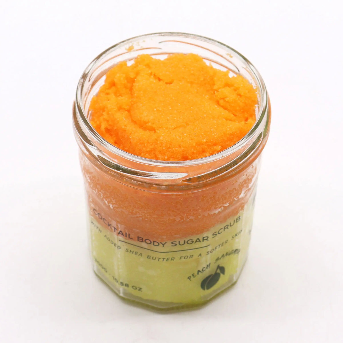 Frasco de cristal con exfoliante de azúcar en capas degradadas de color naranja y amarillo brillante sobre fondo blanco