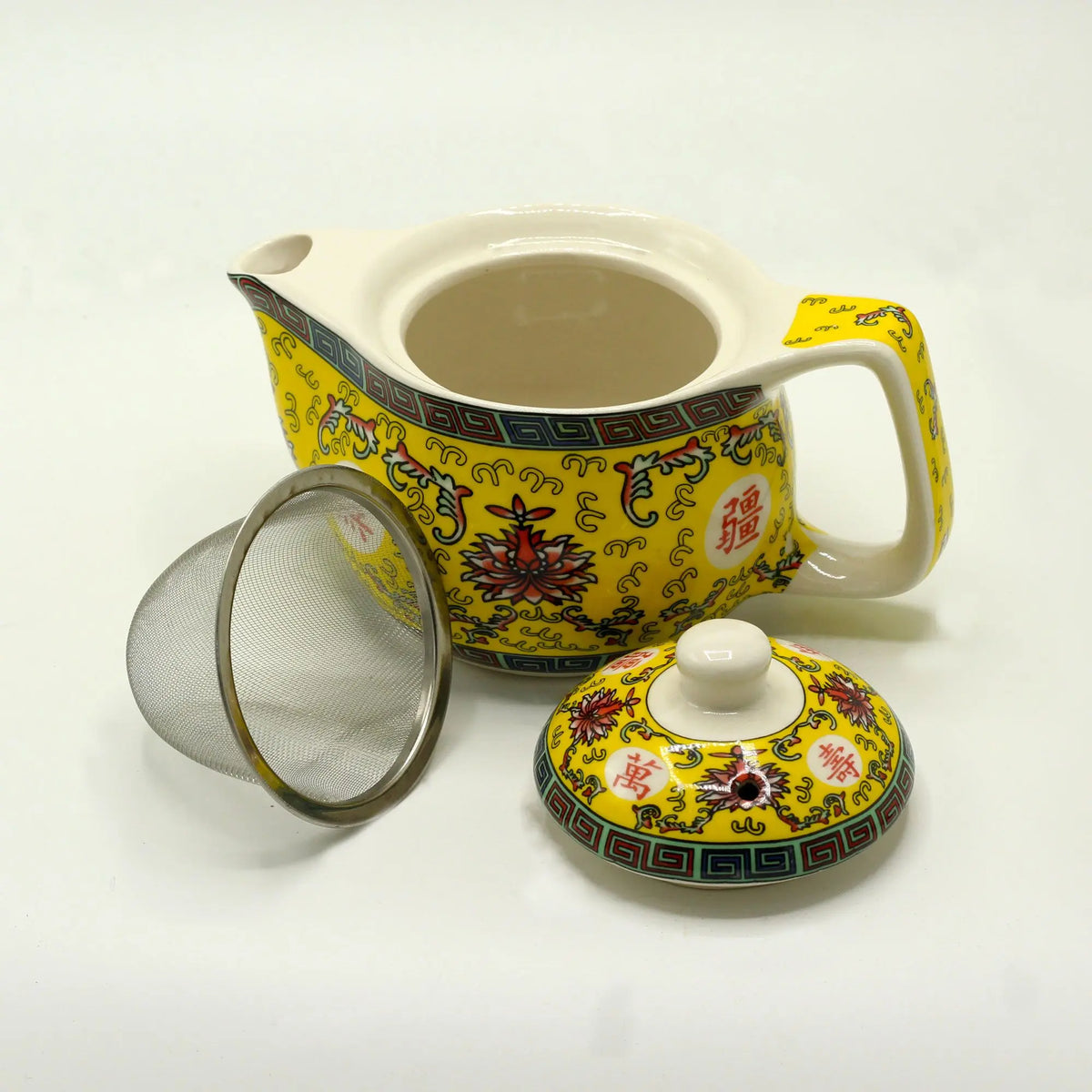 Tetera de cerámica amarilla con motivos orientales, incluye tapa y filtro de malla metálica para infusiones.