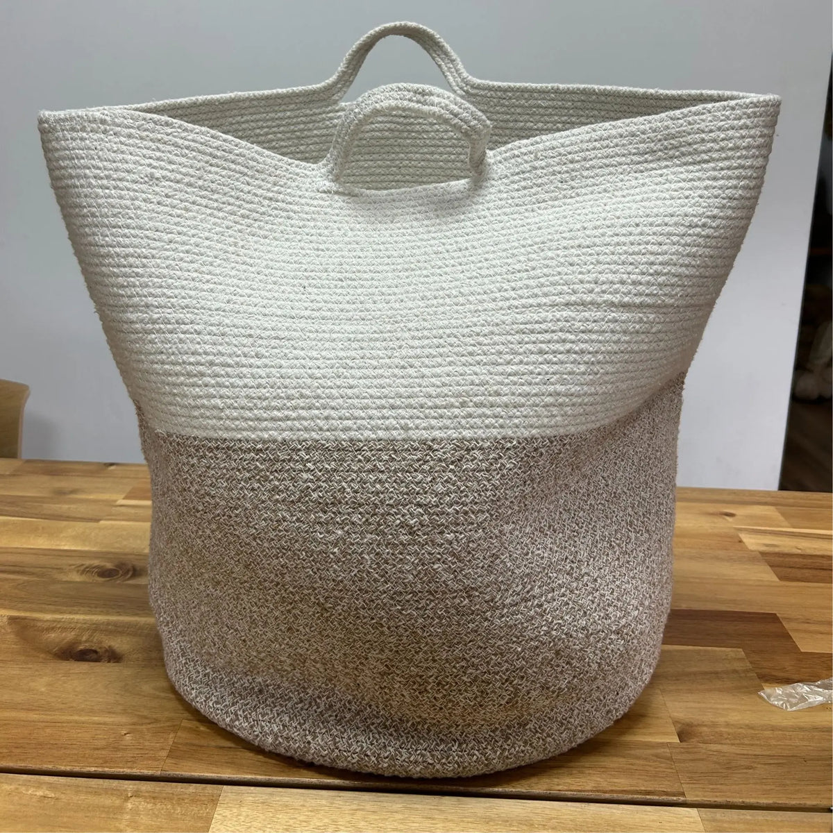 Bolso de mano de yute beige con diseño trenzado, forma amplia y asas, ideal para compras o uso diario.