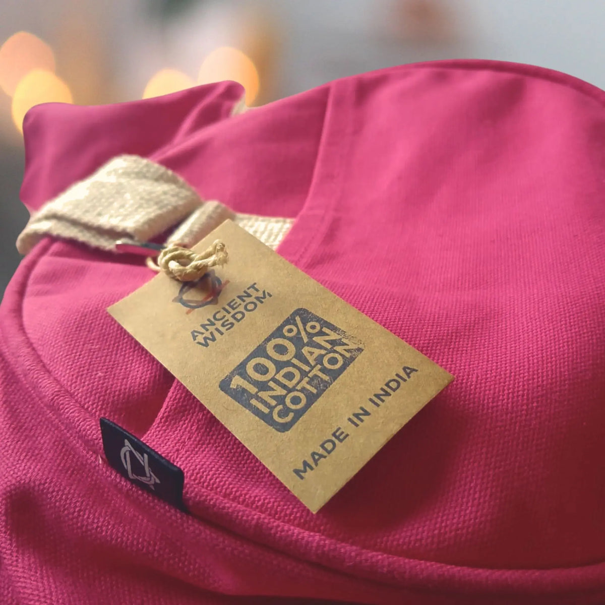 Bolso de gimnasio de algodón rosa cereza con correas color crema y etiqueta informativa de cartón reciclado.