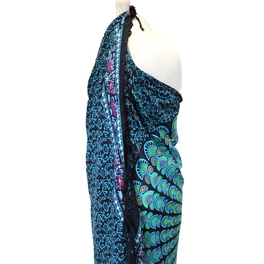 Pareo negro con estampado de mandala y pavo real en tonos azules y verdes, sobre un maniquí. Estilo bohemio.