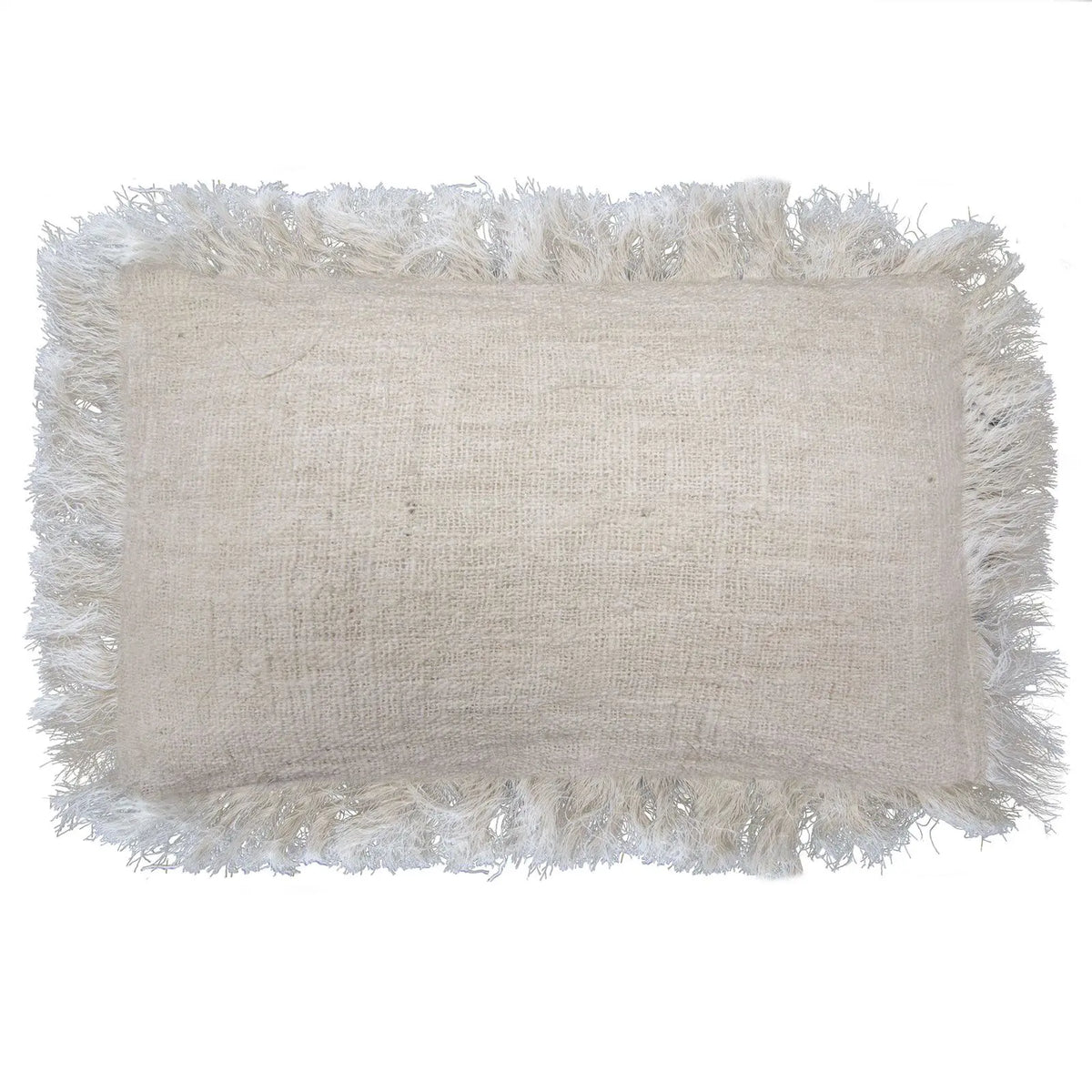 Funda de cojín rectangular de lino color beige con flecos largos en todo el borde, estilo rústico, fondo blanco.