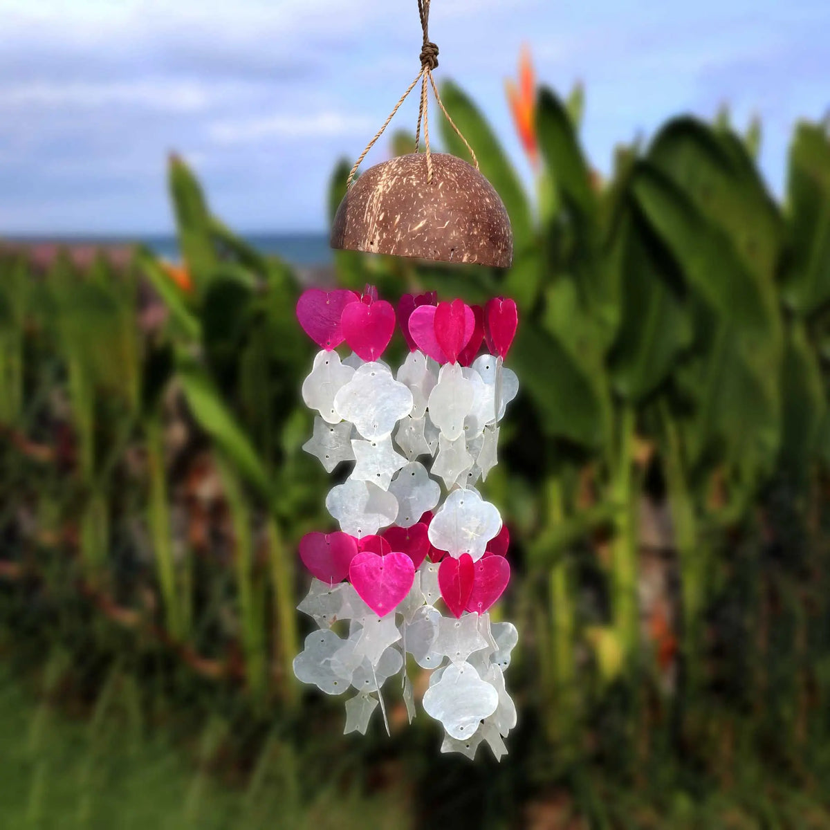 Campanilla de viento artesanal con base de coco y colgantes de concha capiz en formas de corazón rosa y blanco