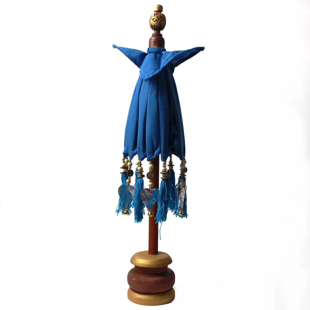 Sombrilla decorativa balinesa turquesa de algodón sobre base de madera con detalles de borlas y abalorios.