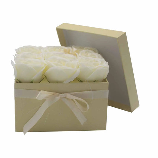 Caja cuadrada color crema con 9 rosas de jabón blancas y lazo, tapa a medio abrir, estilo elegante de regalo.