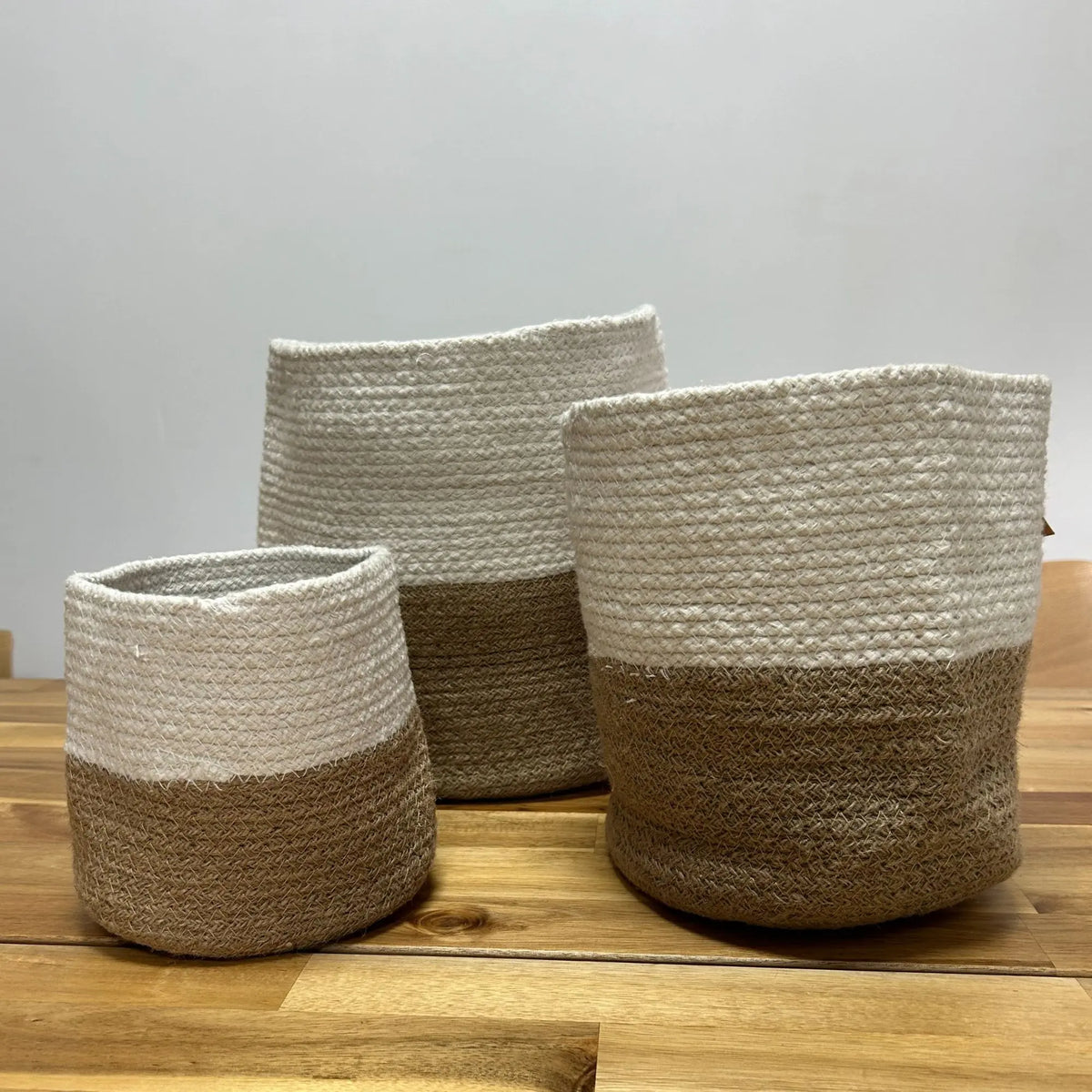 Cestas de fibra natural, en tonos blanco y marrón, con diseño moderno y texturizado, perfectas para organización.