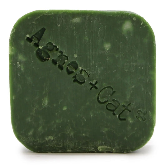 Pastilla de champú sólido verde Agnes + Cat de forma cuadrada con el nombre de la marca grabado en relieve.