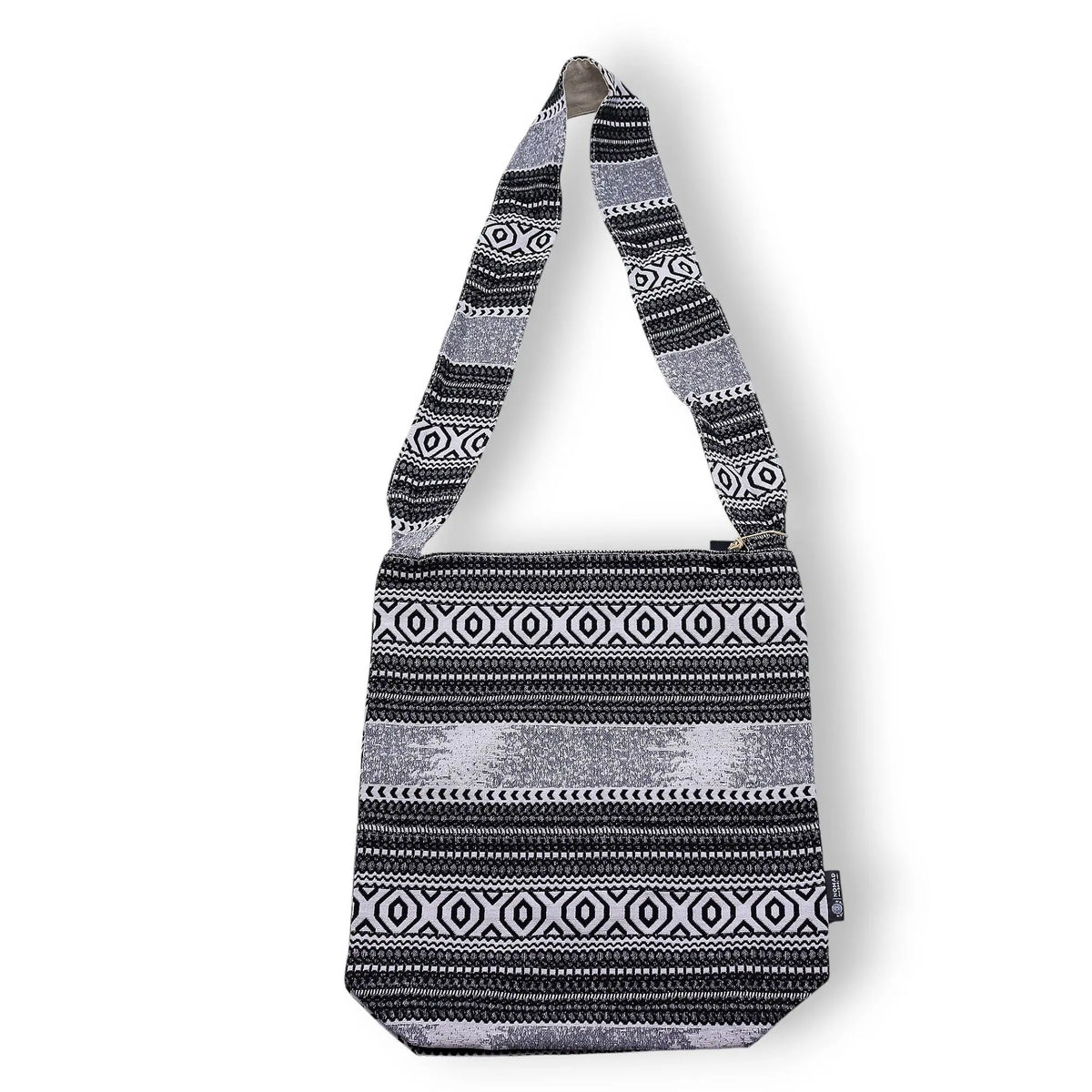 Bolso negro y blanco con diseño étnico, confeccionado en material textil y strap largo para cruzar.
