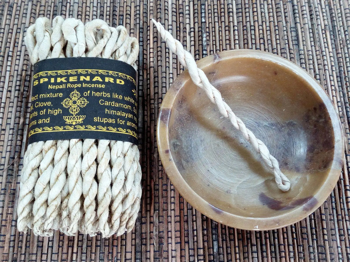 Incienso de cuerda Spikenard, color beige, mezcla de hierbas, con soporte de cerámica en tono marrón.