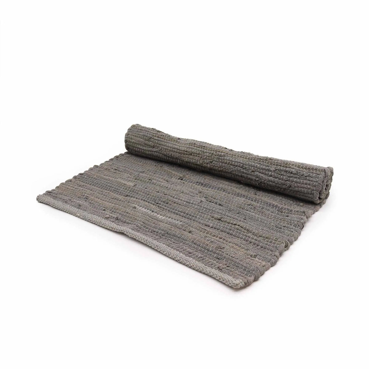 Alfombra rectangular pequeña de algodón tejido a mano, color gris carbón, parcialmente enrollada, sobre fondo blanco.