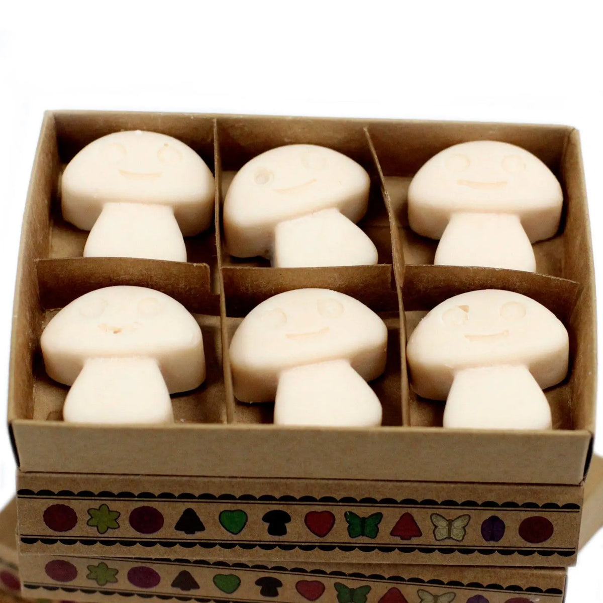 Caja de cartón con 6 piezas de cera de soja blanca en forma de setas con caras sonrientes grabadas. Estilo artesanal.