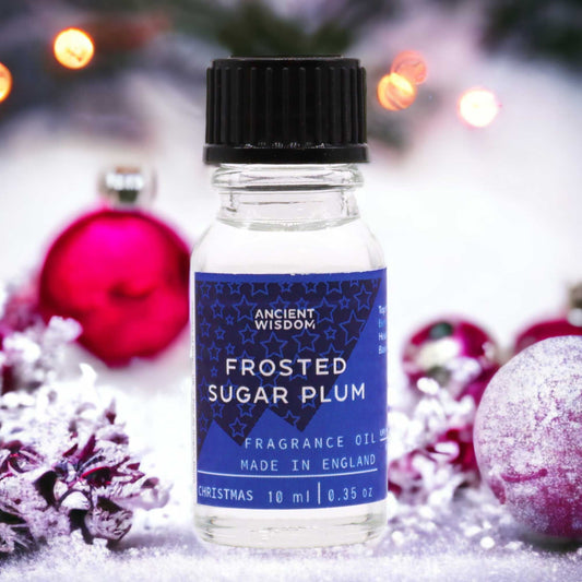 Frasco de cristal de 10 ml con etiqueta azul y tapa negra, sobre fondo festivo con esferas rojas y nieve.
