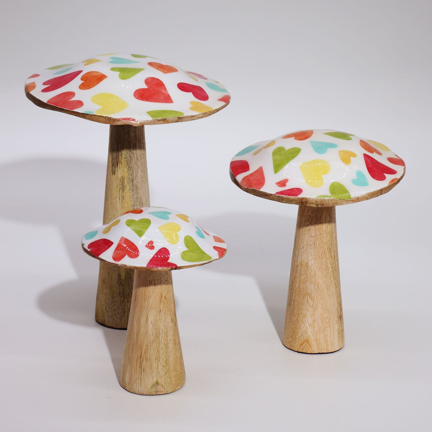 Setas decorativas de madera con sombreretes esmaltados decorados con corazones de colores pastel sobre fondo blanco