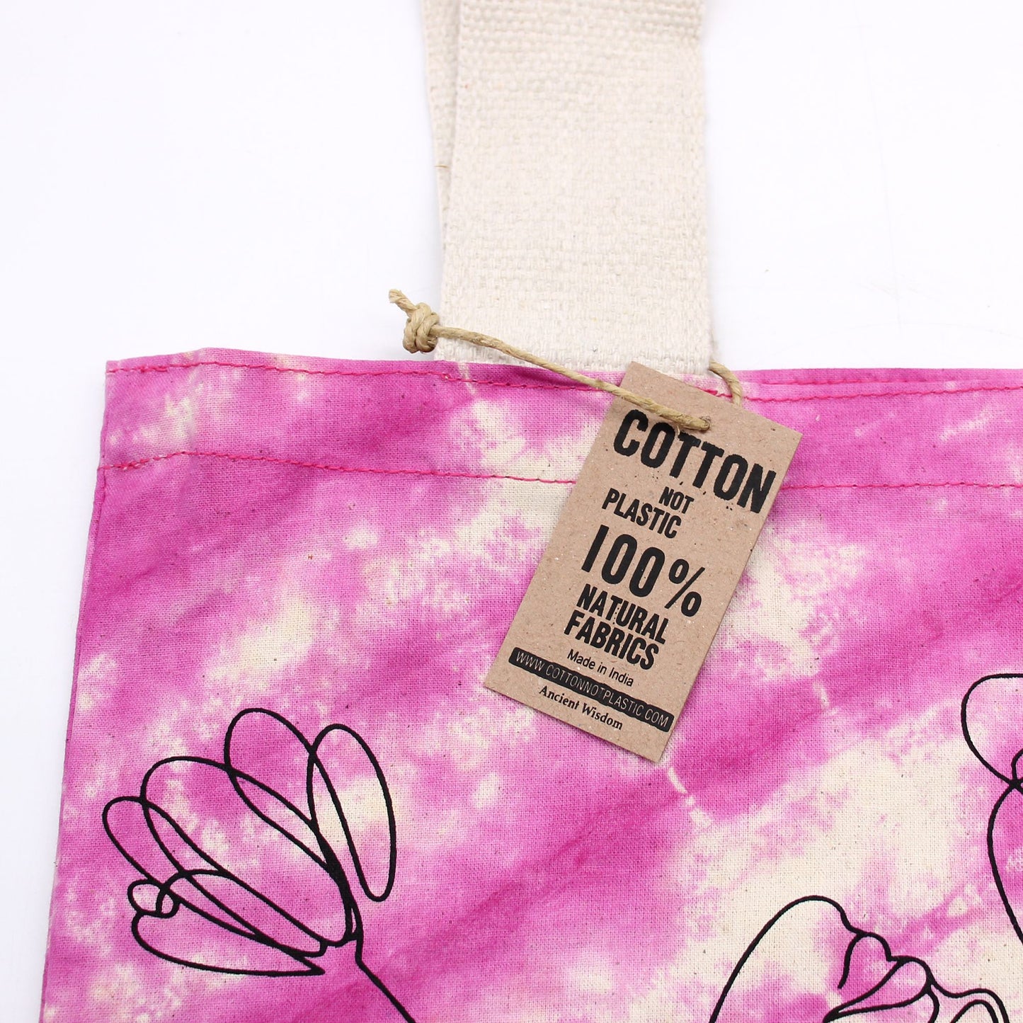Bolsa de algodón tie-dye magenta con diseño de líneas negras y etiqueta de cartón informativa.