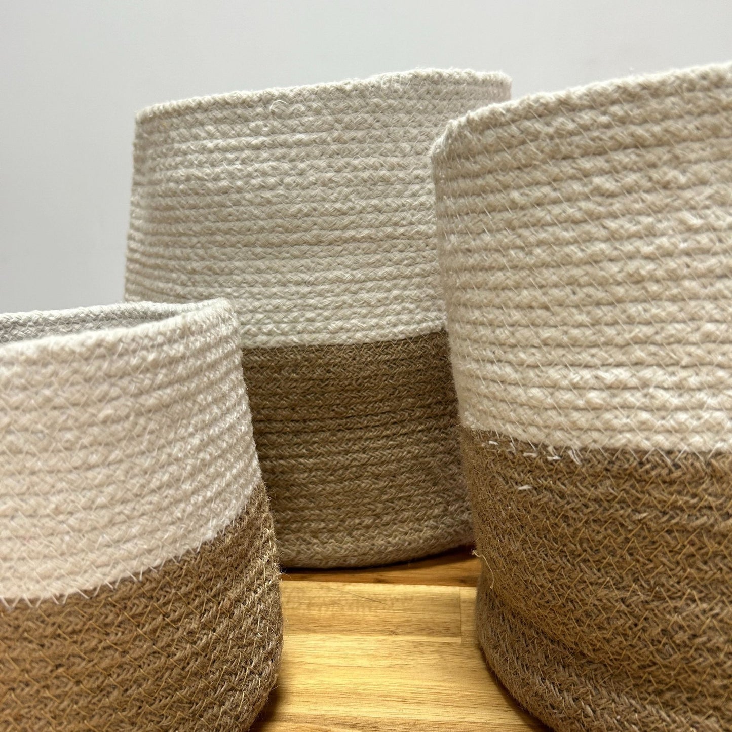 Cestos decorativos de yute y algodón en tonos beige y blanco, ideales para almacenamiento y organización.