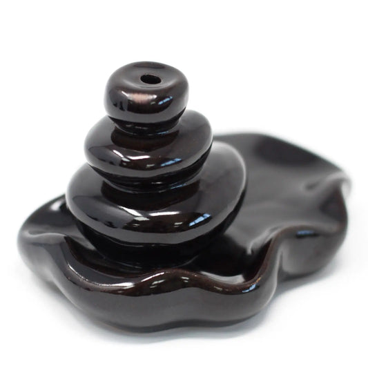 Quemador de incienso de flujo inverso, de cerámica marrón oscura con forma de piedras apiladas sobre una base curva.