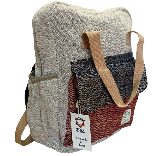 Mochila de cáñamo artesanal, color beige con bolsillo frontal en azul y granate. Estilo casual con asas de tela.