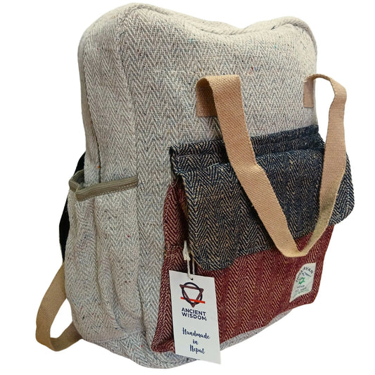 Mochila de cáñamo artesanal, color beige con bolsillo frontal en azul y granate. Estilo casual con asas de tela.
