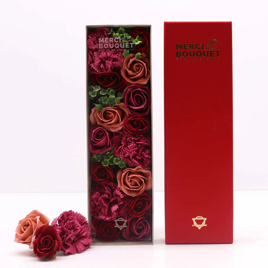 Caja rectangular con rosas y claveles de jabón en tonos vintage, junto a su tapa roja y flores sueltas.