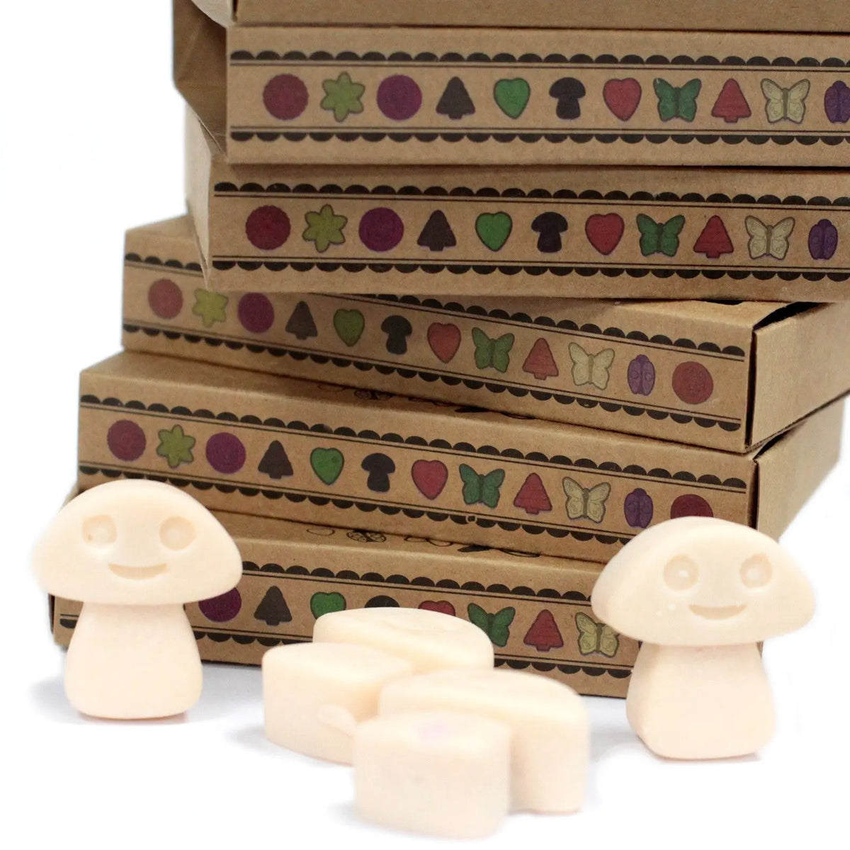 Cajas de cartón kraft con iconos decorativos y ceras de soja claras con forma de seta frente a ellas.
