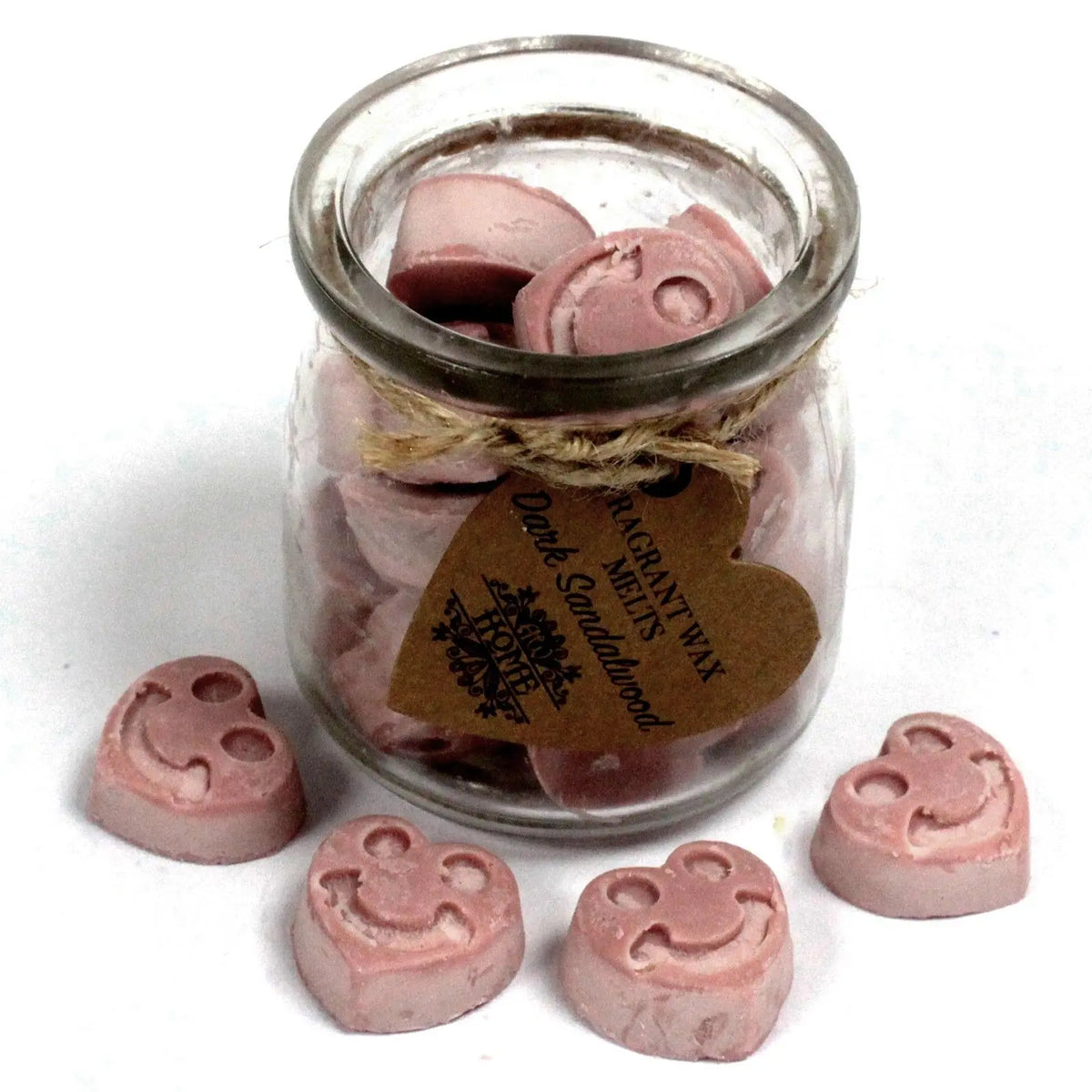 Frasco de vidrio con piezas de cera de soja color malva en forma de corazón con cara sonriente y etiqueta de cartón.