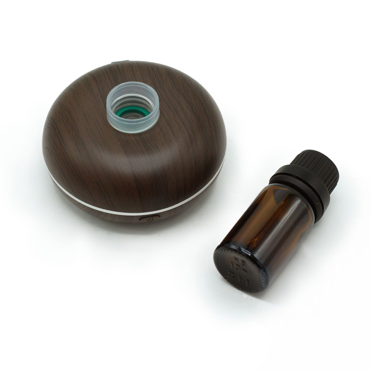 Difusor de aroma circular con acabado de madera oscura junto a un frasco de vidrio ámbar sobre fondo blanco.
