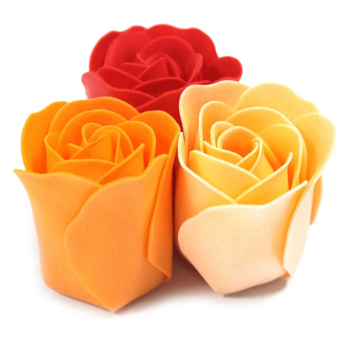 Tres rosas de jabón con pétalos suaves en tonos naranja, amarillo y rojo sobre fondo blanco.