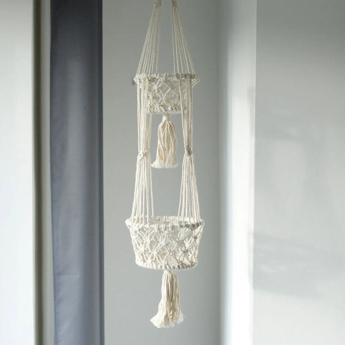 Macramé colgante en color crema con dos cestas decorativas y flecos, ideal para plantas y decoración boho.