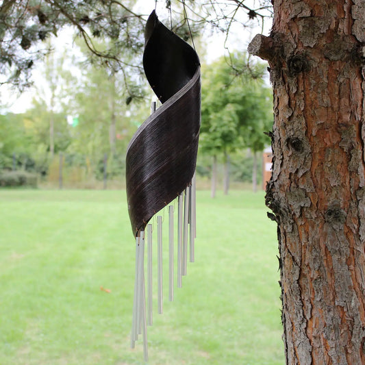 Campanilla de viento de hoja de coco color chocolate con tubos metálicos plateados, colgando de un árbol.